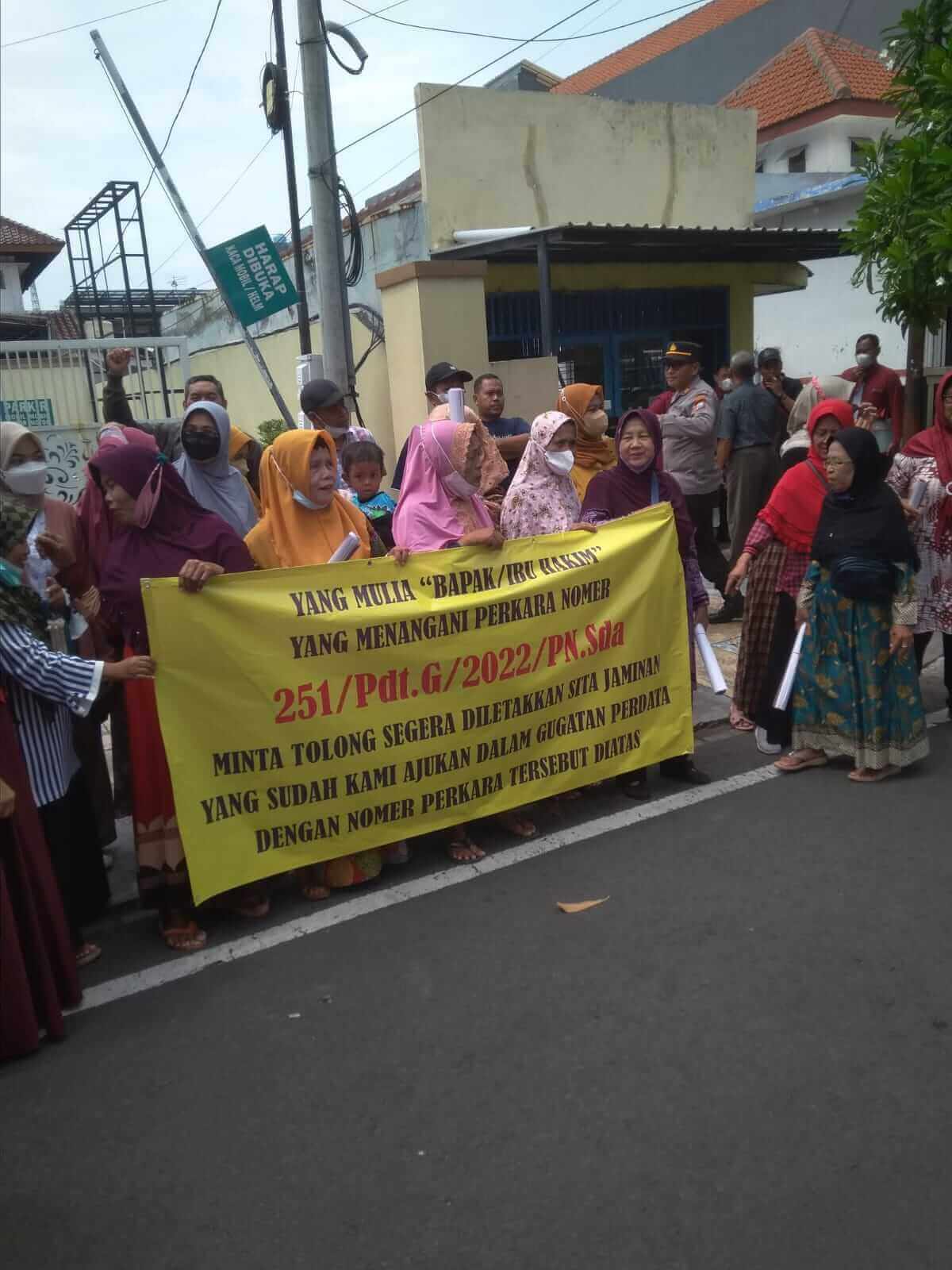 puluhan korban membentangkan spanduk sebelum sidang di pn sidoarjo11