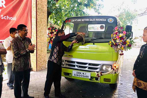 SIMBOLIS: Menguyur Durto 125 ST dengan air kendi. (wul) - Hino Berikan Durto 125 ST ke SMKN 1 Singosari, Persiapkan Tenaga Kerja Kompeten