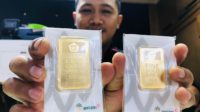 staf toko emas bulan purnama pasar besar kota malang helmi alif yustiansah tengah memegang logam mulia