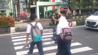 Babinsa Blimbing bantu menyeberang jalan siswa SMP Kartika. (ist) - Berikan Rasa Aman, Babinsa Blimbing Bantu Menyeberang Jalan Siswa SMP Kartika
