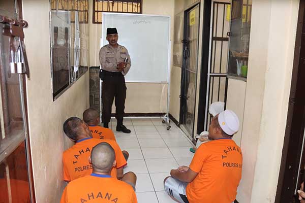 Anggota Polres Batu mengajarkan baca Al Qur’an kepada para tahanan Polres Batu. (ist) - Polres Batu Ajari Tahanan Baca Al Quran