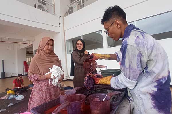 Fikrah menuangkan natol ke kain yang sudah diikat. (jup) - Sulap Baju Bekas Jadi Baju Menarik dengan Teknik Ikat Celup