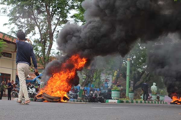 KESAL: Tuntutannya tidak diindahkan, Aliansi Masyarakat Pamekasan membakar ban di depan kantor Bupati Pamekasan. (udi) - Pilkades 2023 Pamekasan Resmi Ditunda, Massa Aksi Bakar Ban di Kantor Bupati