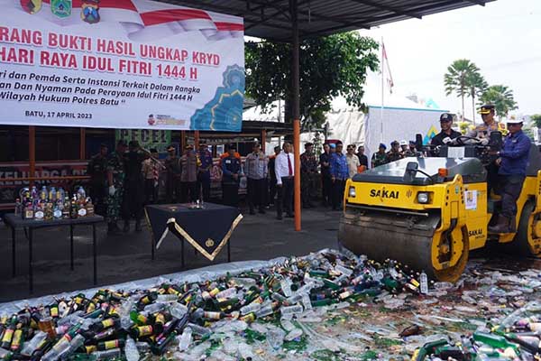 Kapolres Batu menjalankan alat berat drum roller untuk memusnahkan BB miras. (ist) - Jelang Lebaran, Polres Batu Musnahkan Ribuan Botol Miras dan Belasan Gram Sabu