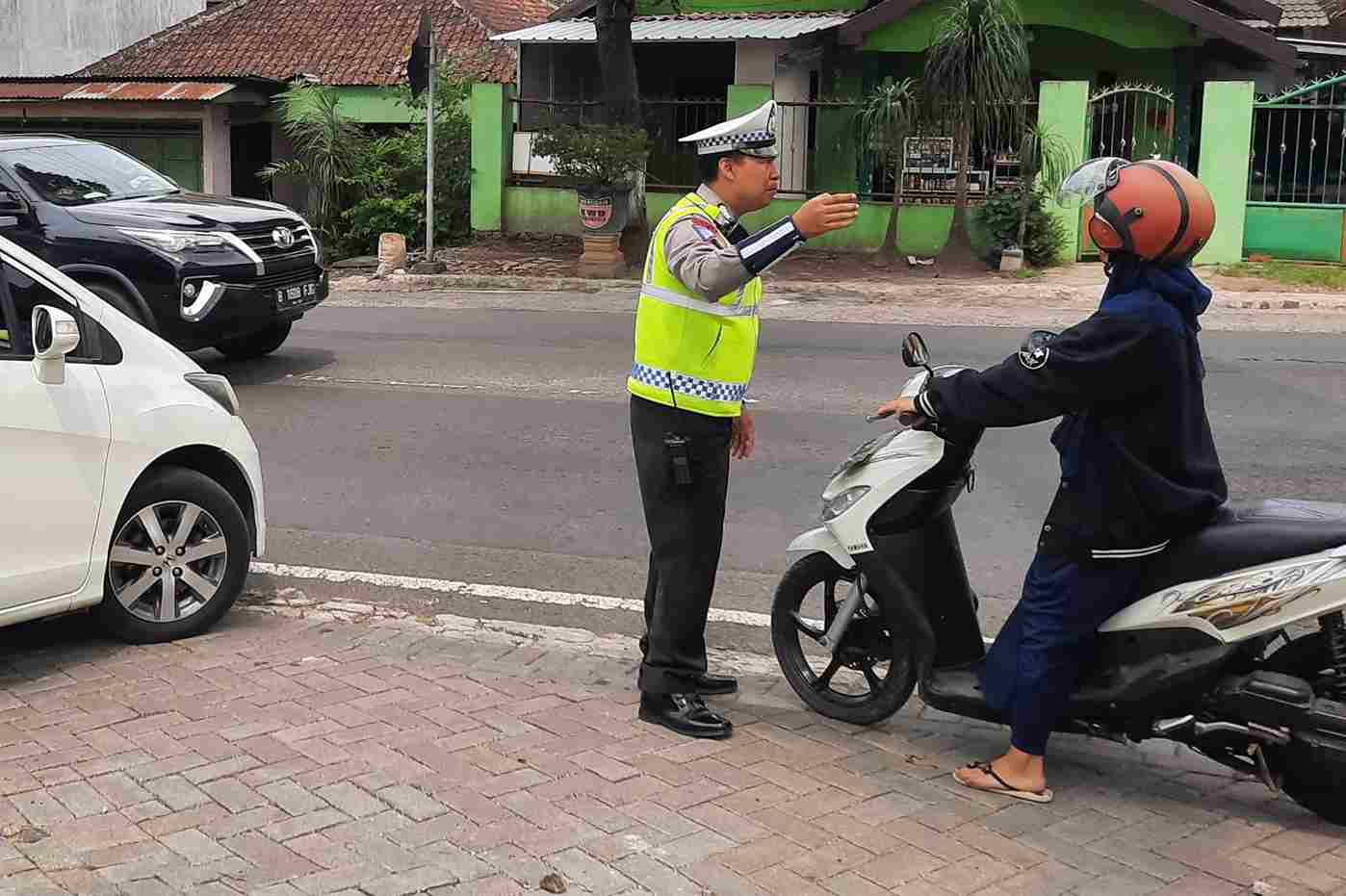 petugas menghentikan kendaraan yang mencoba melawan arah saat uji coba satu arah diberlakukan