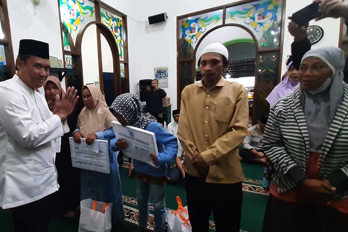 Sekda Kota Batu, Zadim Efisiensi menyerahkan Bansos dari Pemkot Batu kepada perwakilan penerima. (dik) - Pesan Safari Ramadan Hari Keenam Pemkot Batu di Masjid Roudotul Amni