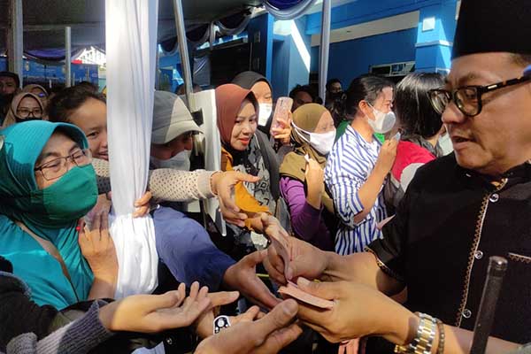 Wali Kota Malang, Sutiaji, membagikan uang baru kepada masyarakat yang sedang antre. (rhd) - Ribuan Warga Malang Tumplek Blek Tukar Uang Baru di Gedung Kartini