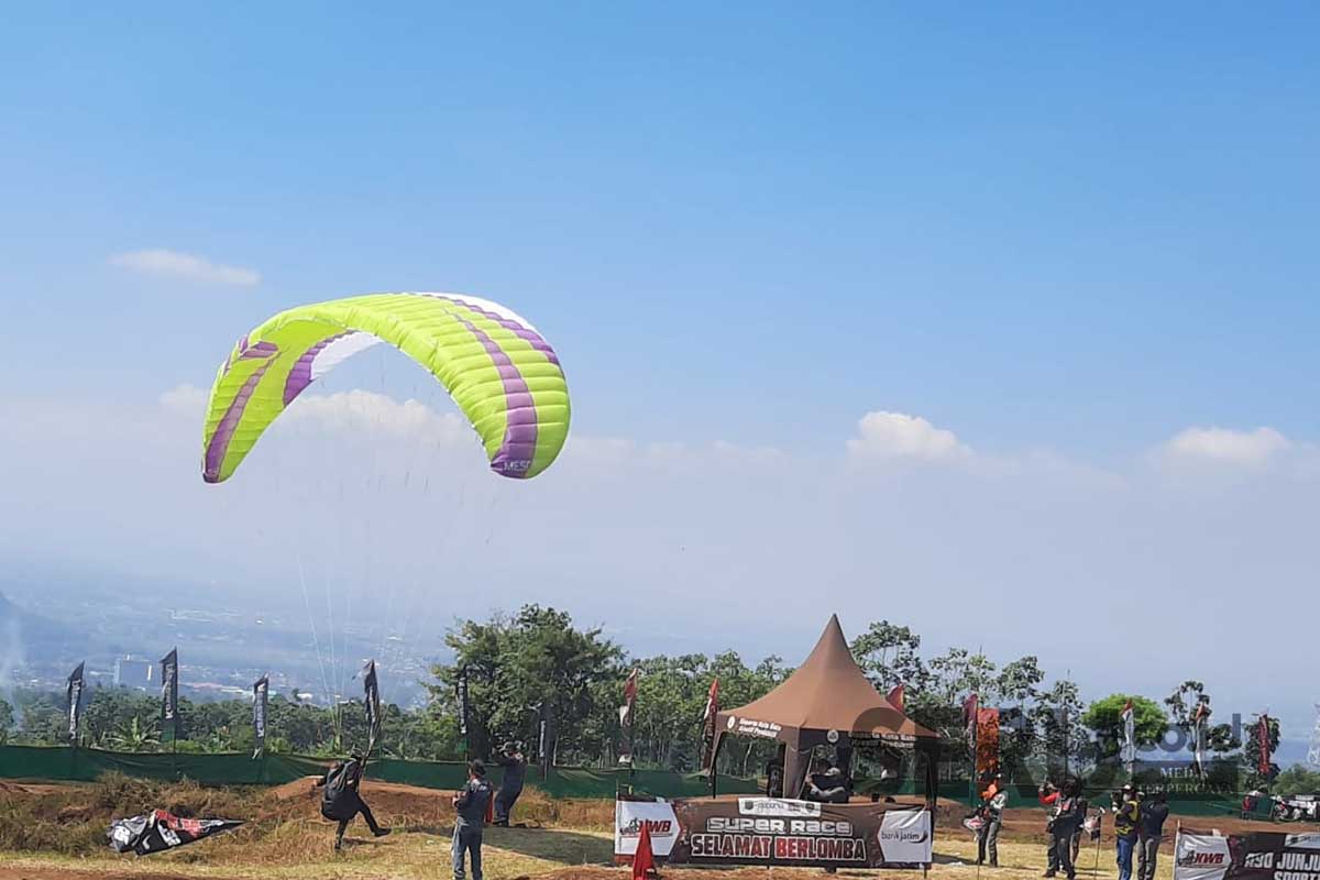 Penerbang paralayang menghibur penonton disela-sela break race. (dik) - KWB Motocross and Grasstrack Championship 2023, Upaya Disparta Batu Kejar Target Kunjungan Wisata