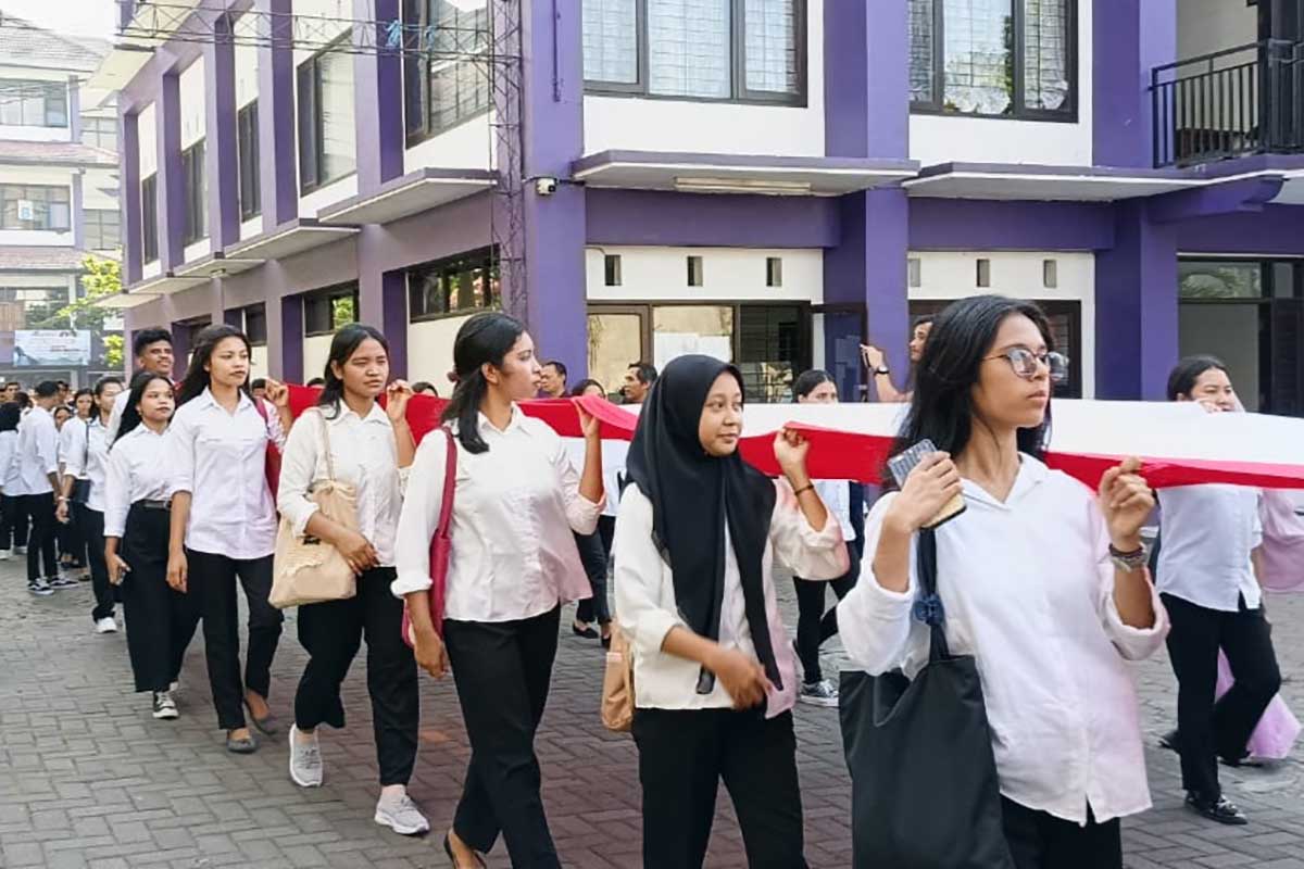 Mahasiswa Unitri membentangkan bendera merah putih yang dikirab dari kampus utama ke kampus Scient Techno Park. (rhd) - Pentas Budaya Unitri Peringati Hardiknas dan Harlah Pancasila