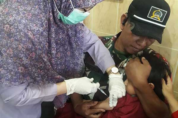Babinsa Cemorokandang ikut menenangkan balita peserta imunisasi ORI difteri. (ist) - Babinsa Cemorokandang Dampingi Imunisasi ORI Difteri Balita