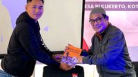 Dr Mondry (kanan) menyerahkan buku 'Media dan Bencana' kepada Ketua Karangtaruna Desa Bulukerto. (Mondry for SERU.co.id) - Mondry: Pentingnya Manfaatkan Media Angkat Isu Lingkungan dan Bencana