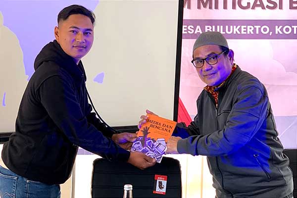 Dr Mondry (kanan) menyerahkan buku 'Media dan Bencana' kepada Ketua Karangtaruna Desa Bulukerto. (Mondry for SERU.co.id) - Mondry: Pentingnya Manfaatkan Media Angkat Isu Lingkungan dan Bencana