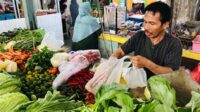 Nasir tengah melakukan transaksi jual beli di lapak sayurnya, yang berada di Pasar Bunul, Kecamatan Blimbing, Kota Malang. (Seru.co.id/wul) - Gagal Panen Dampak Kemarau Ekstrem, Harga Cabai Tembus Rp80 Ribu
