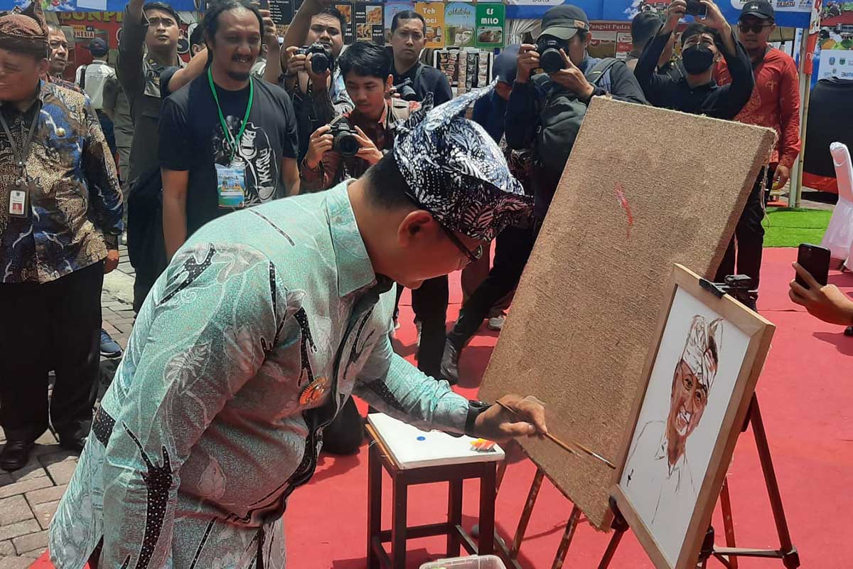 Pj. Wali Kota Batu menyempatkan diri menggoreskan kuas lukis untuk diteruskan oleh seniman. (dik) - Sejumlah Daerah Ramaikan Expo Pariwisata dan Ekraf #3 Disparta Batu