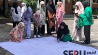 Para mahasiswa Unira membubuhkan tandatangan di atas spanduk. (Seru.co.id/wul) - BEM Unira Kepanjen Gelar Tanda tangan Petisi Dukung Pemilu Damai