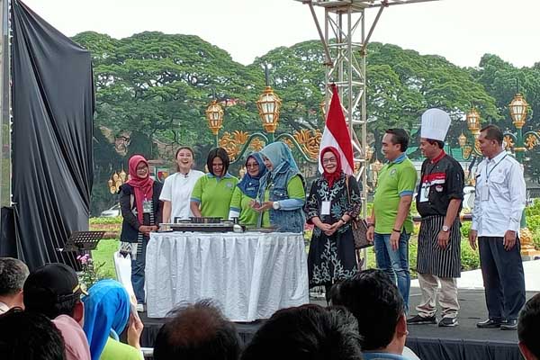 Pj Ketua PKK Kota Malang menyalakan kompor, simbolisasi dimulainya perlombaan. (afi) - TP-PKK Kota Malang Tantang 35 Peserta Racik Makanan Berbahan Tempe, Nila dan Bunga Telang