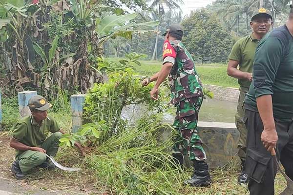 Babinsa Kedungkandang bersama linmas dan warga Tlogowaru bersihkan bantaran sungai. (ist) - Babinsa Kedungkandang Bersama Linmas dan Warga Tlogowaru Bersihkan Bantaran Sungai