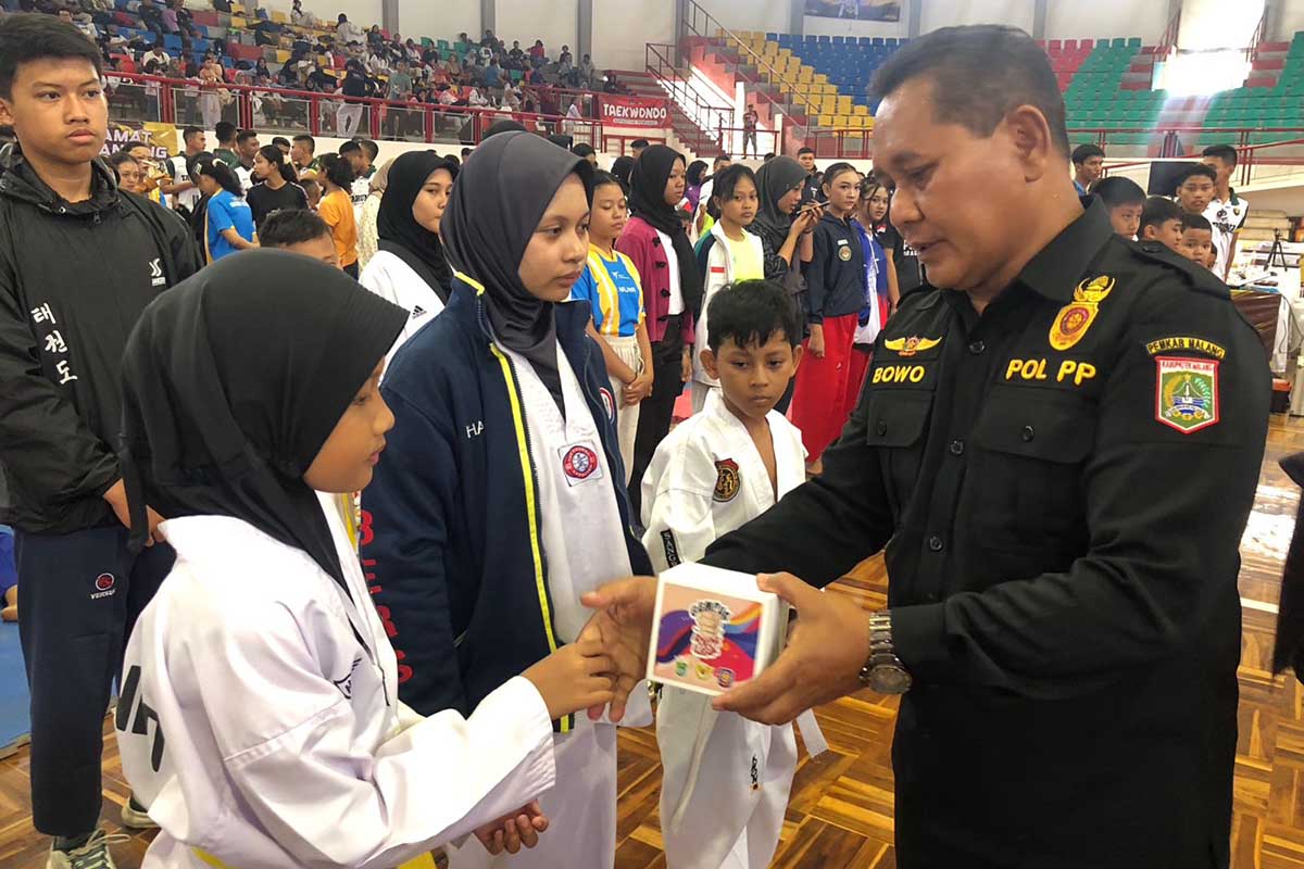 Kepala Bidang Penegakan Peraturan Daerah Satpol PP Kabupaten Malang, Bowo menyerahkan suvenir untuk para peserta. (wul) - Pemkab Malang dan Bea Cukai Sosialisasi Gempur Rokok Ilegal Melalui Kejuaraan Taekwondo