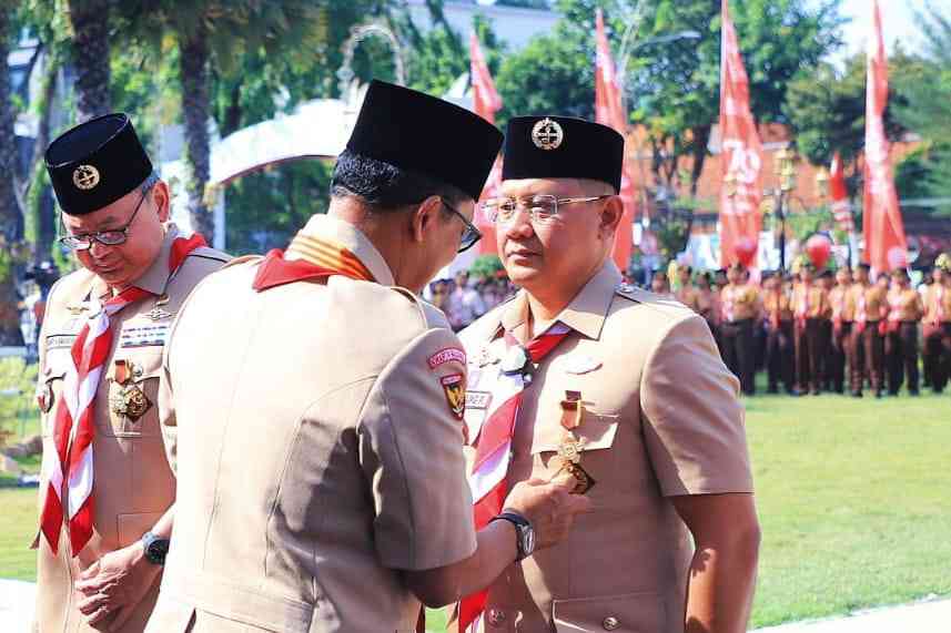 Peduli Gerakan Pramuka, Pj Wali Kota Batu Terima Penghargaan Lencana Darma Bakti Surabaya, SERU.co.ud - Penjabat (Pj) Wali Kota Batu, menerima penghargaan Lencana Darma Bakti dari Kwartir Nasional (Kwarnas) Gerakan Pramuka, Selasa (27/8/2024). Penghargaan di berikan di Gedung Negara Grahadi di Surabaya oleh Ketua Kwarnas Pramuka Komjen Pol (Purn) Budi Waseso. Penyerahan penghargaan di berikan dalam kegiatan Upacara Hari Pramuka Ke - 63, Kwartir Daerah Gerakan Pramuka Jawa Timur. Penghargaan Lencana Darma Bakti ini diberikan kepada individu yang telah menyumbangkan tenaga, pikiran, dana dan fasilitas cukup besar. Serta dinilai sangat membantu kelancaran kegiatan pembinaan dan pengembangan Gerakan Pramuka. Pj. Wali Kota Batu, Dr Aries Paewai sekaligus sebagai Ketua Majelis Pembimbing Cabang (Mabicab) Gerakan Pramuka Kota Batu. Dalam riwayat kepramukaannya, Pj. Aries sudah merintis sebagai anggota pramuka sejak masih sekolah dasar, dan aktif diseluruh tingkatan pramuka. Bahkan jiwa pramuka ini melekat sampai Pj. Aries menjalani pendidikan di IPDN. "Sejak kecil, saya telah belajar banyak hal berharga dari Gerakan Pramuka," serunya. Berbagai pengalamannya sebagai anggota pramuka diantaranya Raimuna Tingkat Penegak dan Pandega Nasional sampai internasional di Lebak Harjo, Kabupaten Malang Tahun 1993. Bahkan juga pernah mengantarkannya mengikuti kegiatan sampai ditingkat Jambore Pramuka Dunia di Korea Tahun 1991. Selain itu, Aries juga mendapatkan tiga rekor MURI, antara lain, apel akbar pramuka serentak dengan kemah terbanyak, pagelaran macapat oleh pramuka terbanyak, dan pelatihan siaga bencana oleh pramuka terbanyak. "Penghargaan ini bukan hanya untuk saya, tetapi juga untuk seluruh anggota pramuka yang terus berjuang untuk negeri," kata Pj. Aries. Ditengah hilangnya identias pramuka, Pj. Aries berinisiasi menghidupkan eksistensi pramuka dengan secara terang menolak dan mewajibkan pramuka sebagai ekstrakulikuler wajib di sekolah. Ia juga mencanangkan revitalisasi gerakan pramuka pada kegiatan Apel Akbar Pramuka Penegak dan Pelatihan Kepramukaan Tingkat Penegak se-Jawa Timur di Kota Batu. Penghargaan yang ia terima, didedikasikan untuk seluruh anggota Pramuka, agar terus bersemangat untuk menjadikan Pramuka sebagai tempat menempa diri. "Untuk menjadi generasi penerus dan pemimpin masa depan bangsa yang beriman, kokoh, tangguh, cinta alam dan kasih sayang sesama manusia," pungkas Pj. Aries Jiwa kepemimpinan yang diperoleh dari kegiatan kepramukaan, kini mengantar Aries Agung Paewai berprestasi diberbagai bidang, menginsiprasi banyak orang. Aries pun dipercaya menjadi Pj. Wali Kota Batu, sekaligus Kepala Dinas Pendidikan Provinsi Jawa Timur, dan sebagai Andalan Kwarda Gerakan Pramuka Jatim. Selain itu juga dilaksanakan penyerahan penghargaan Lencana Melati kepada Pj Gubernur Jatim Adhy Karyono yang juga Ketua Majelis Pembimbing Daerah (Mabida) Gerakan Pramuka masa bakti 2024-2025. (dik/...) Gerakan Pramuka, Pj Wali Kota Batu, Penghargaan Lencana Darma Bakti