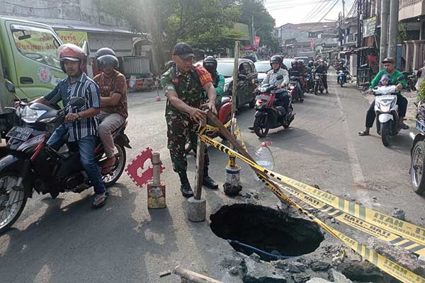 Babinsa Kotalama pasang rambu peringatan jalan amblas. (ist) - Babinsa Kotalama Pasang Rambu Peringatan Jalan Amblas