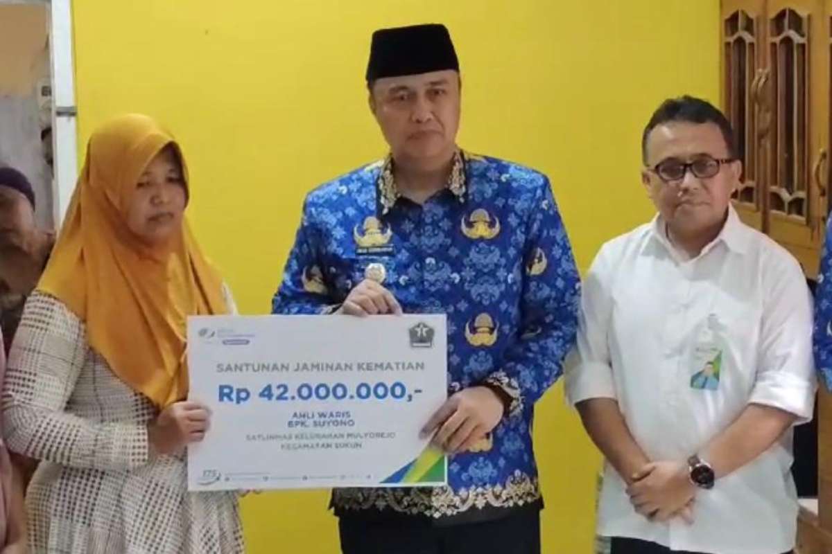 Pj Wali Kota Malang, Iwan Kurniawan menyerahkan, bantuan dari BPJS Ketenagakerjaan kepada istri almarhum. (ist) - Pj Wali Kota Malang Takziah dan Serahkan Bantuan Satlinmas Pilkada Meninggal Dunia