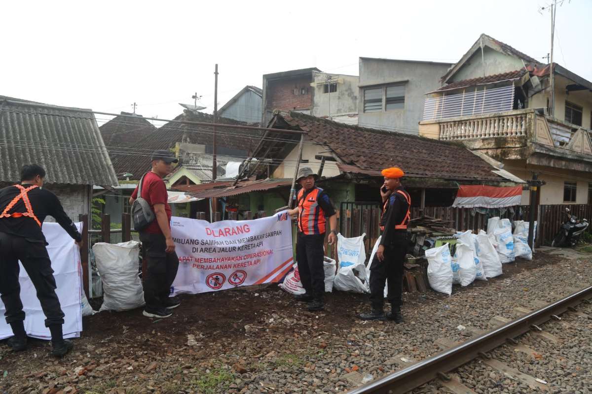 Petugas KAI Daop 8 Surabaya sedang memasang poster ‘Dilarang membuang dan membakar sampah di jalur KA.’ (ist) - Sterilisasi Jalur KA Malang-Pakisaji, KAI Siapkan Nataru yang Aman