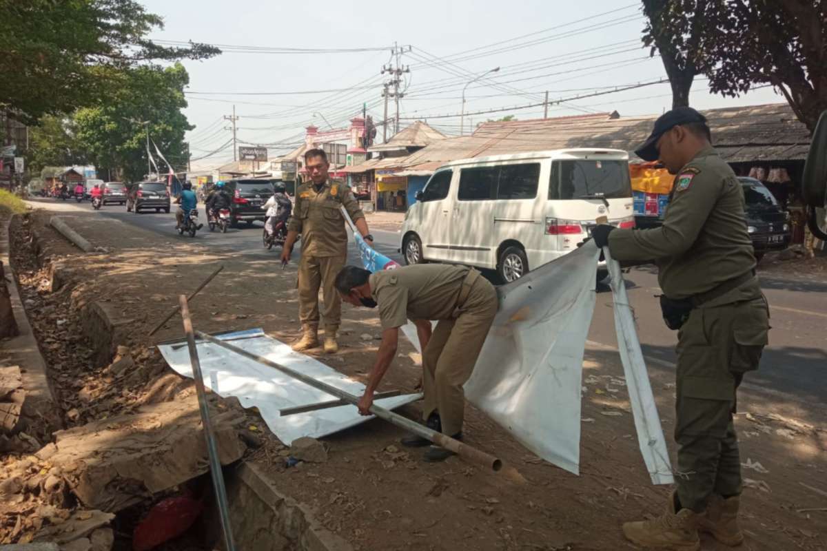 Anggota Satpol PP Kabupaten Malang melakukan penertiban reklame kedaluwarsa. (ist) - Satpol PP Kabupaten Malang Tertibkan Puluhan Reklame Kedaluwarsa