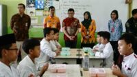 Kementerian PANRB sedang memantau siswa yang sedang makan bergizi gratis. (pro) - Kementerian PANRB Tinjau Program Makan Bergizi Gratis di Malang