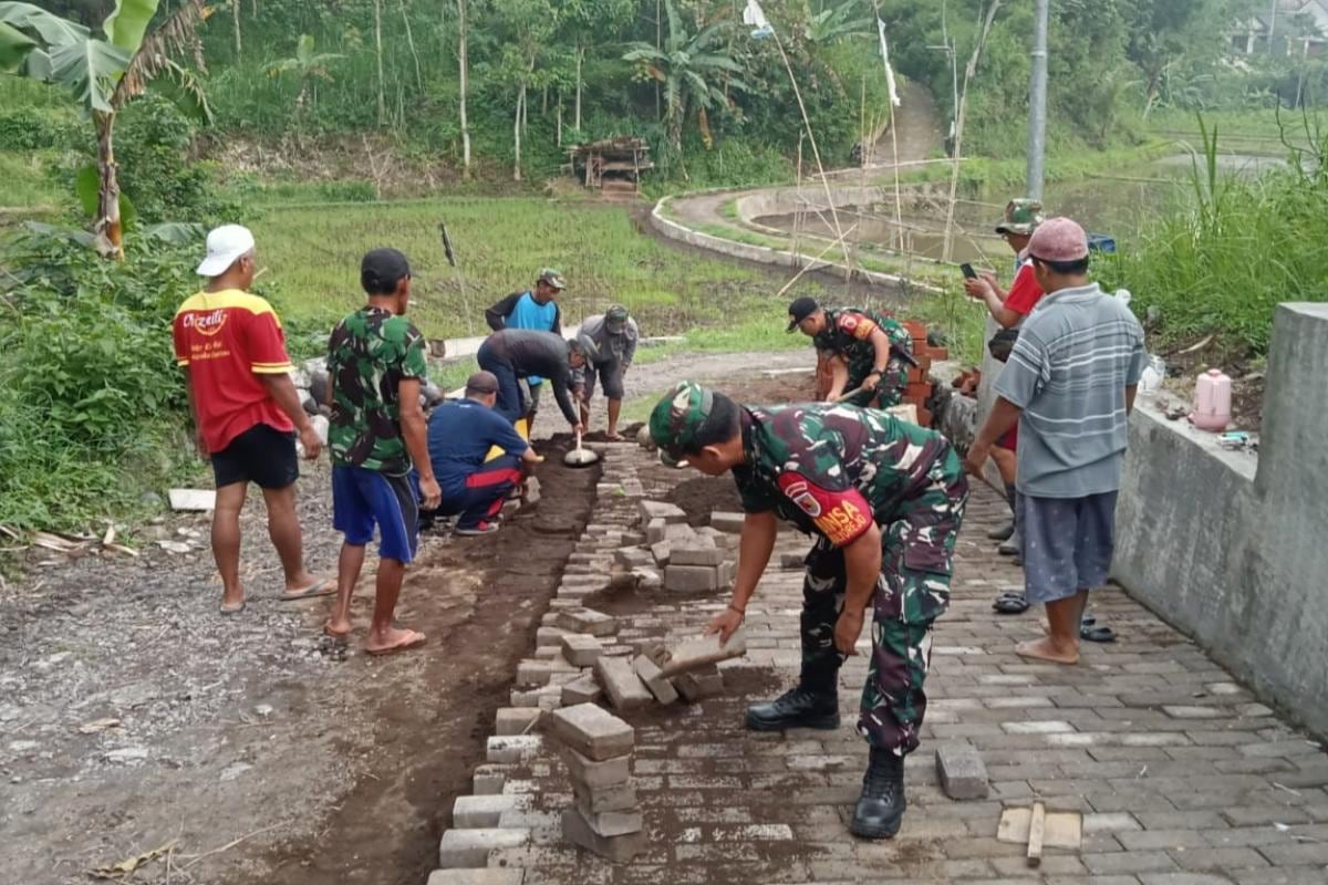 Babinsa Mulyorejo Bantu Warga Pasang Paving di Lingkungan Pemukiman