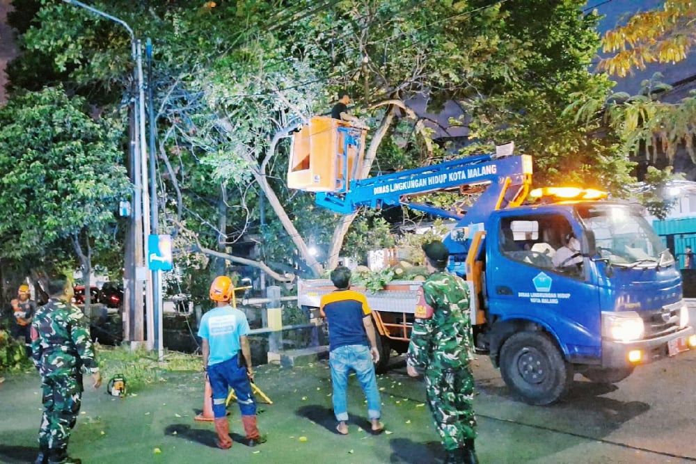Babinsa Sawojajar dampingi evakuasi ranting pohon tumbang tersangkut kabel listrik. (ist) Babinsa Sawojajar Dampingi Evakuasi Ranting Pohon Tumbang Tersangkut Kabel Listrik