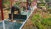 Proses pemasangan papan_11zon Anggota Koramil Klojen Bersama Masyarakat Gotong Royong Pasang Papan Jembatan Perintis Garuda
