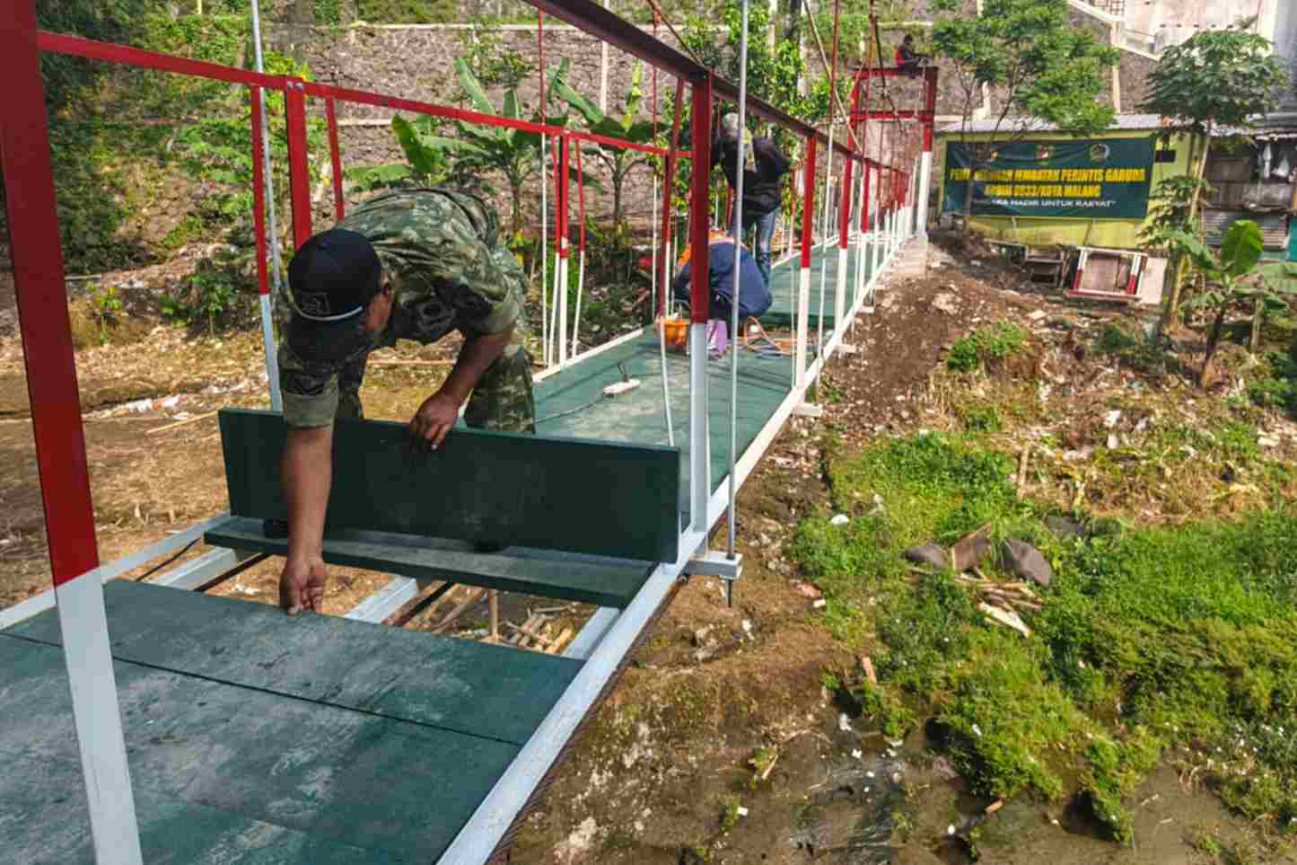 Proses pemasangan papan_11zon Anggota Koramil Klojen Bersama Masyarakat Gotong Royong Pasang Papan Jembatan Perintis Garuda