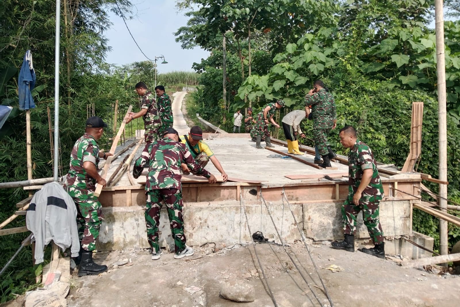 Personel Koramil Sukun bersama warga menyusun rangka pagar Jembatan Perintis Garuda. (ist) Personel Koramil Sukun Turun Tangan Rakit Rangka Pagar Jembatan Perintis Garuda